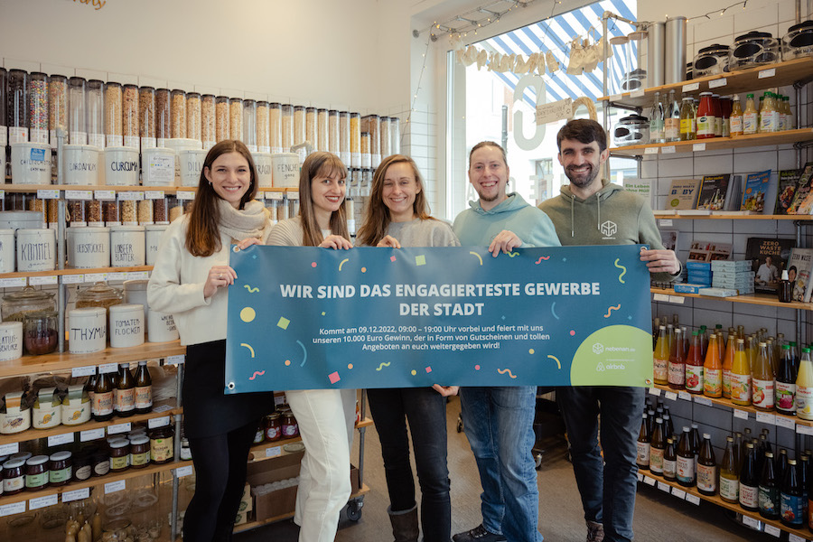 Fünf Personen stehen in einem Unverpackladen und halten ein Banner hoch auf dem steht 